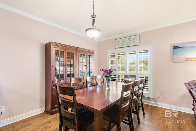 dining space with crown molding and light wood-type flooring