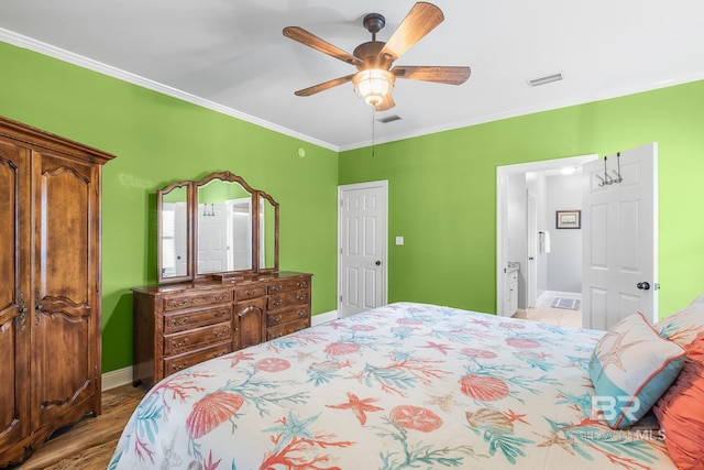 bedroom featuring ceiling fan, ensuite bath, wood-type flooring, and ornamental molding