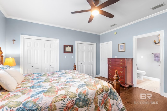 bedroom with ceiling fan, ensuite bathroom, two closets, crown molding, and hardwood / wood-style flooring