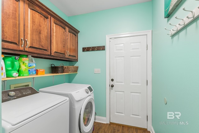 clothes washing area featuring dark wood-type flooring, washer and dryer, and cabinets