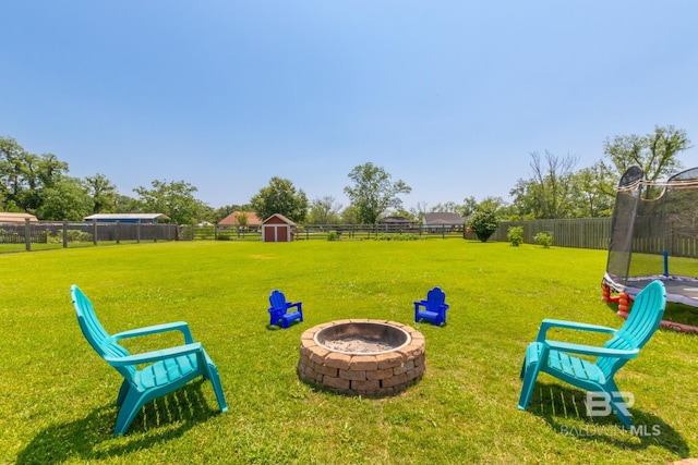 exterior space featuring a storage shed, a fire pit, and a trampoline