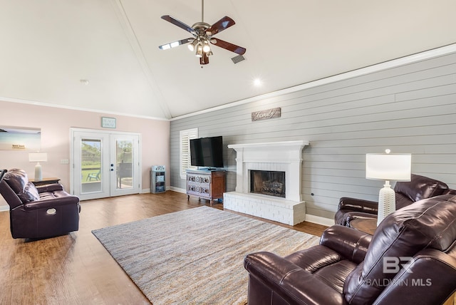 living room featuring lofted ceiling, wood walls, crown molding, and french doors