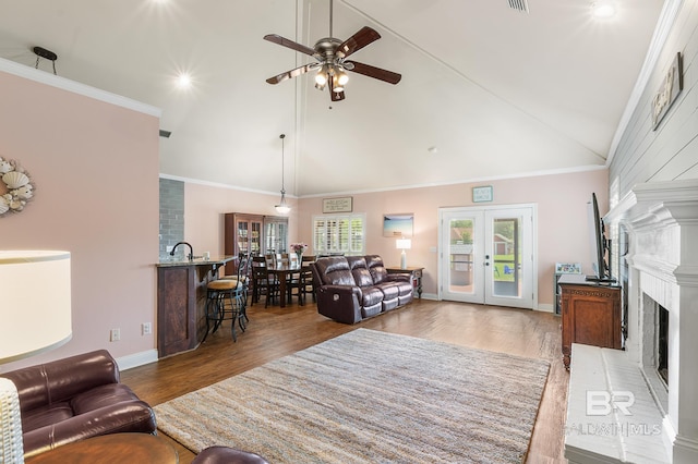 living room featuring vaulted ceiling, a brick fireplace, crown molding, and wood-type flooring