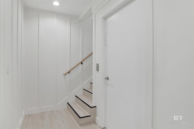 staircase featuring wood finished floors and a decorative wall