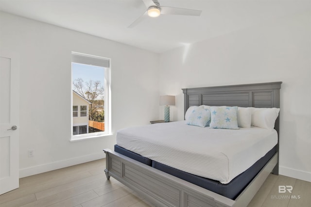 bedroom featuring ceiling fan, light wood-style flooring, and baseboards