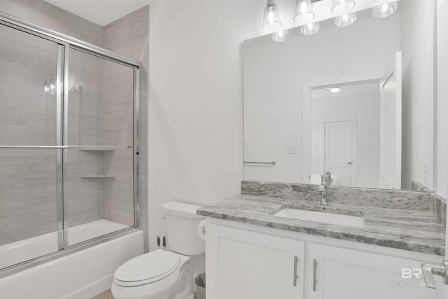 full bath with toilet, bath / shower combo with glass door, and vanity