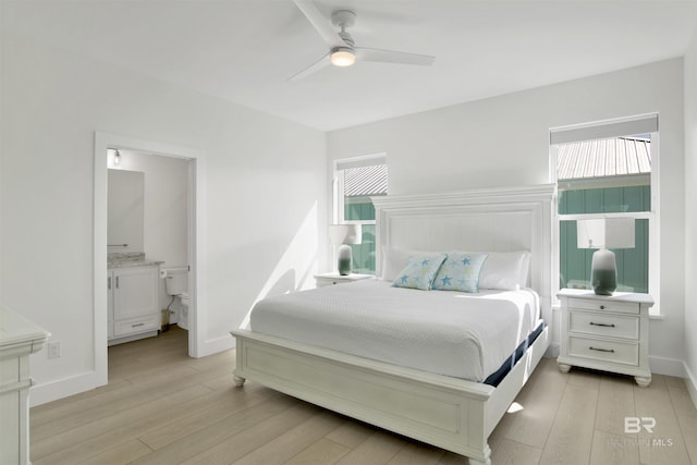 bedroom with ceiling fan, light wood-style flooring, baseboards, and ensuite bathroom