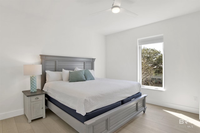 bedroom featuring a ceiling fan, light wood-style flooring, and baseboards