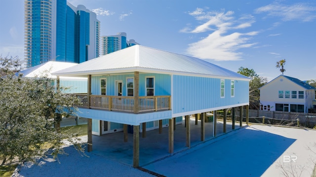 back of property with driveway, a view of city, fence, and a carport