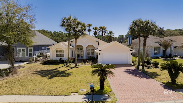 view of front of house featuring an attached garage, stucco siding, decorative driveway, and a front yard