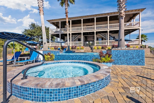 view of swimming pool featuring stairway, a hot tub, and a patio