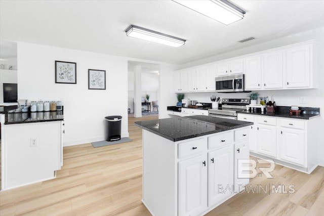 kitchen featuring white cabinetry, appliances with stainless steel finishes, a kitchen island, and light wood-type flooring