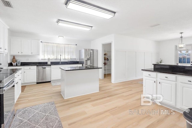 kitchen featuring white cabinetry, pendant lighting, a kitchen island, light hardwood / wood-style floors, and stainless steel appliances