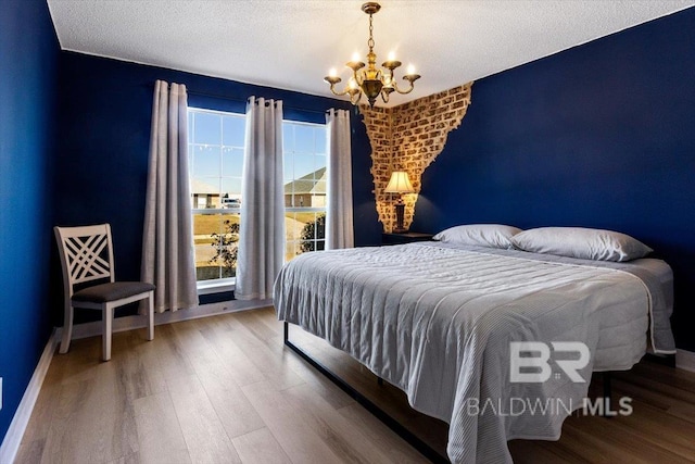 bedroom with a textured ceiling, hardwood / wood-style flooring, and a chandelier