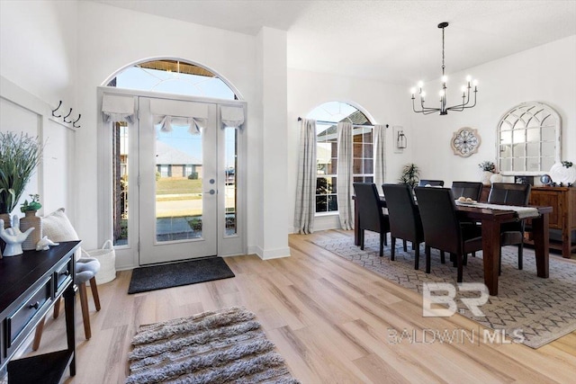 foyer entrance with an inviting chandelier, a healthy amount of sunlight, and light hardwood / wood-style flooring