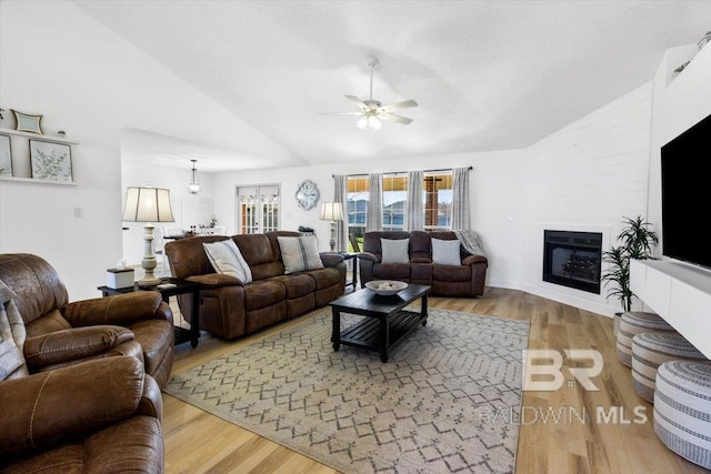 living room featuring lofted ceiling, ceiling fan, light hardwood / wood-style flooring, and a fireplace