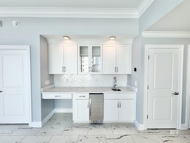 kitchen with crown molding, light countertops, white cabinets, marble finish floor, and a sink