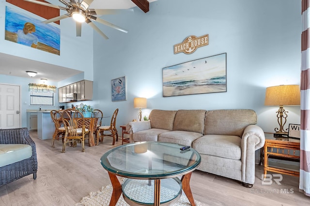 living room featuring a ceiling fan, light wood-style floors, and a towering ceiling