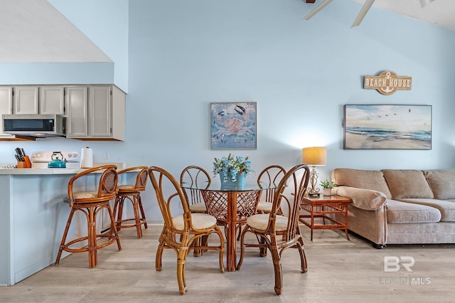 dining area with light wood-style floors and a high ceiling