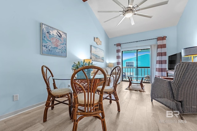 dining room with baseboards, high vaulted ceiling, light wood-style flooring, and a ceiling fan