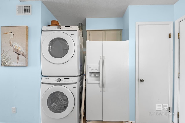 washroom with stacked washer / dryer, cabinet space, a textured ceiling, and visible vents