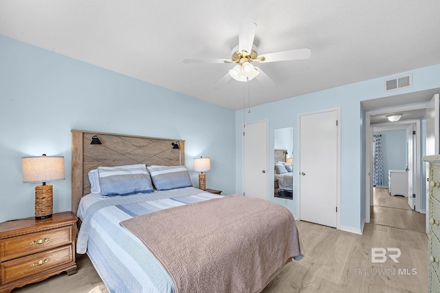 bedroom with light wood finished floors, visible vents, and a ceiling fan