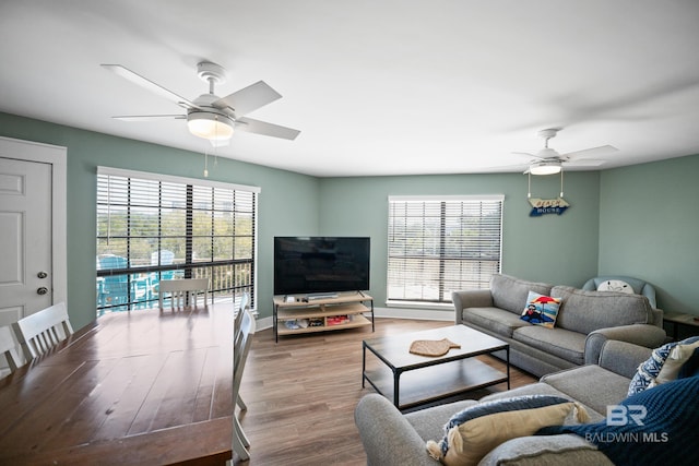 living room with ceiling fan, healthy amount of natural light, wood finished floors, and baseboards