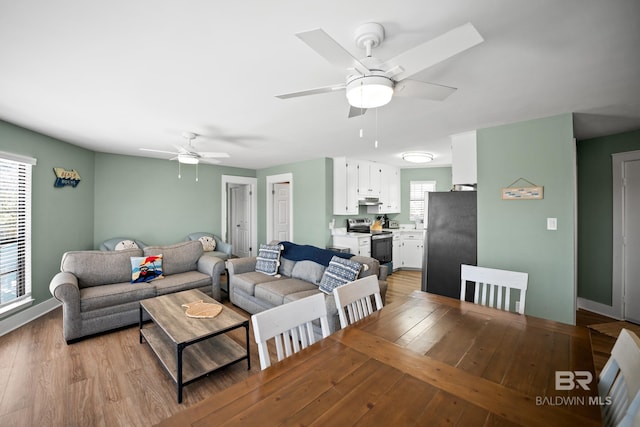 living room with ceiling fan, light wood finished floors, and baseboards