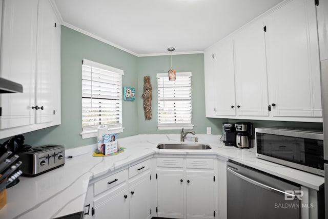 kitchen with appliances with stainless steel finishes, a sink, white cabinets, light stone countertops, and ornamental molding
