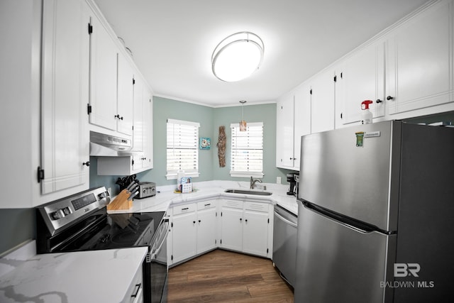kitchen with appliances with stainless steel finishes, under cabinet range hood, a sink, white cabinetry, and crown molding