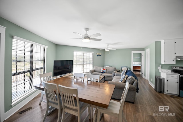 dining room with dark wood-style floors, a ceiling fan, and baseboards