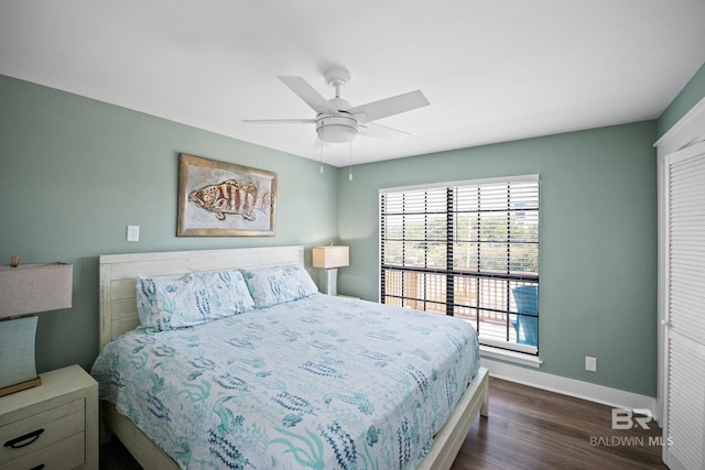bedroom featuring dark wood-style floors, baseboards, a ceiling fan, and a closet