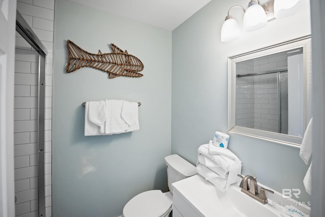 bathroom with toilet, tiled shower, and a sink