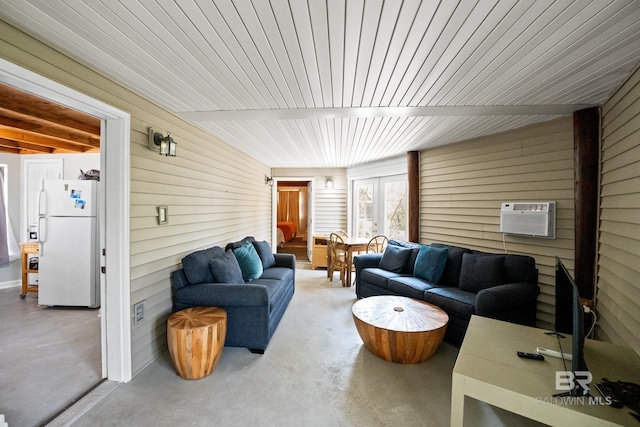 living area with a wall mounted air conditioner, concrete flooring, and wooden walls