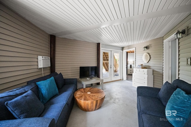 living room featuring wood walls, french doors, concrete flooring, and a wall unit AC