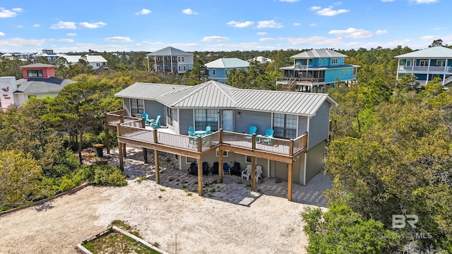 back of property featuring metal roof, driveway, a wooden deck, an attached garage, and a residential view