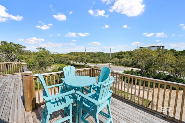 wooden deck featuring outdoor dining area and view of wooded area