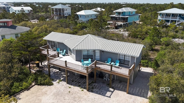 rear view of house with metal roof, a wooden deck, and a balcony