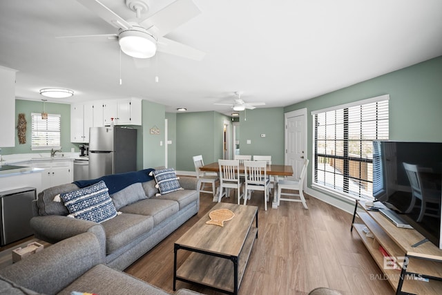 living area featuring a ceiling fan, wood finished floors, and baseboards