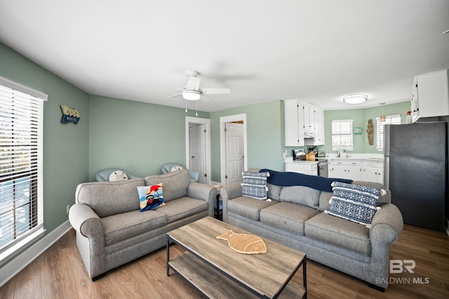 living room with wood finished floors, ceiling fan, and baseboards