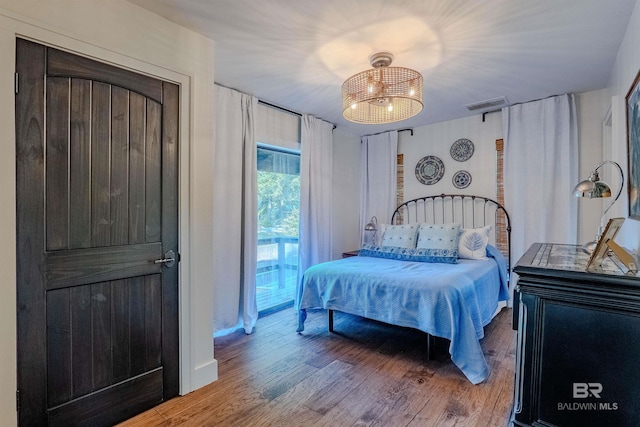 bedroom with ceiling fan with notable chandelier, hardwood / wood-style floors, and access to outside