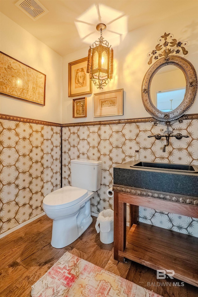 bathroom featuring hardwood / wood-style flooring, sink, an inviting chandelier, and toilet