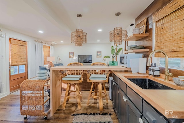 kitchen featuring wood counters, sink, hardwood / wood-style flooring, and hanging light fixtures