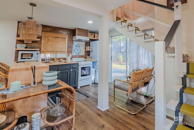 kitchen featuring wood counters, sink, white range with gas stovetop, hanging light fixtures, and light wood-type flooring