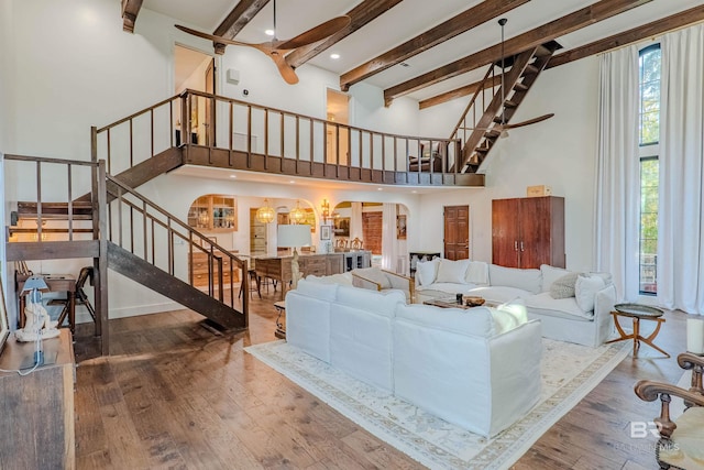 living room with hardwood / wood-style flooring, beamed ceiling, and a high ceiling