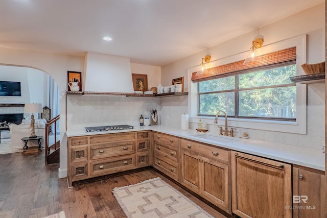 kitchen with stainless steel gas stovetop, sink, backsplash, and dark hardwood / wood-style floors