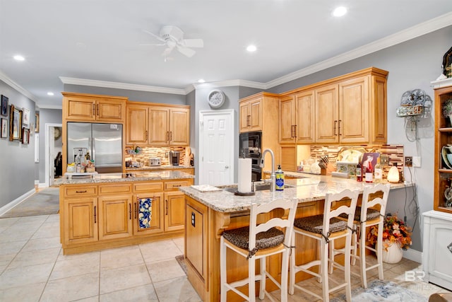 kitchen with a breakfast bar, light tile patterned flooring, stainless steel refrigerator, crown molding, and ceiling fan