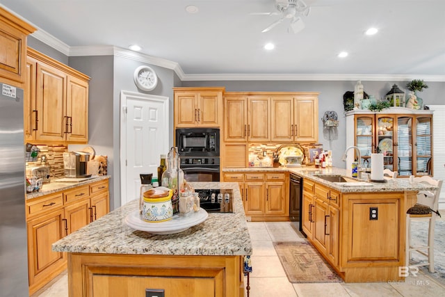 kitchen with light stone counters, sink, a center island with sink, black appliances, and decorative backsplash