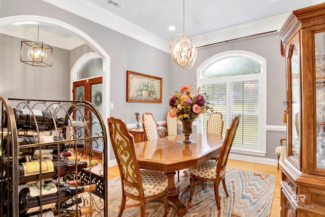 dining room featuring light hardwood / wood-style flooring, a notable chandelier, and crown molding