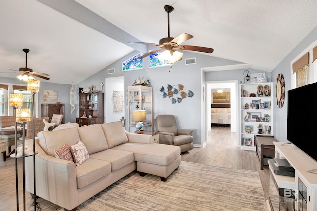 living room featuring lofted ceiling with beams, a wealth of natural light, ceiling fan, and light hardwood / wood-style floors